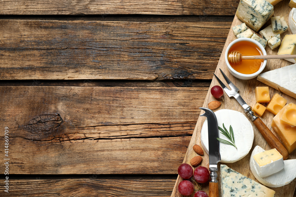 Cheese platter with specialized knife and fork on wooden table, flat lay. Space for text Cheese platter with specialized knife and fork on wooden table, flat lay. Space for text