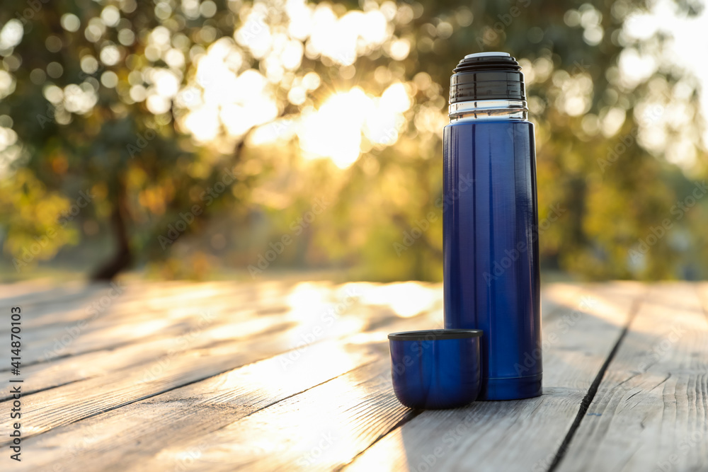 Modern blue thermos on wooden surface outdoors. Space for text Modern blue thermos on wooden surface outdoors. Space for text