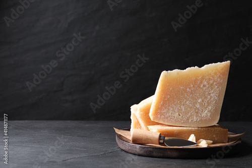 Delicious parmesan cheese with knife on black table. Space for text