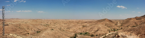 Beautiful idyllic far panoramic view over the deserts in north africa in tunasia showing hills, dunes, nature and a wide horizon with blue sky and few clouds.