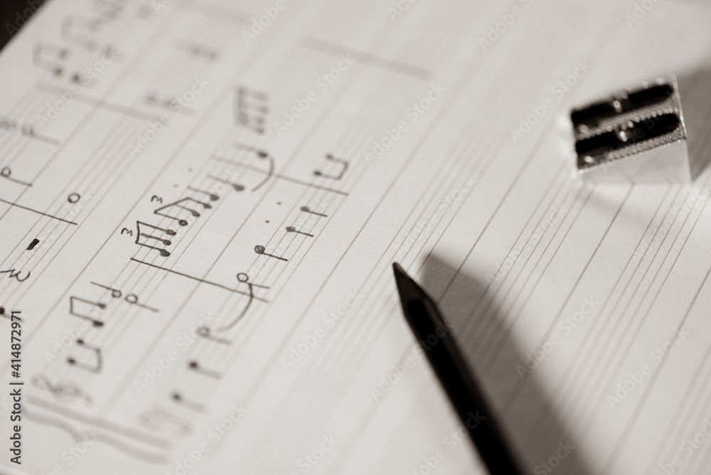 orchestral or piano score written by a music master, music written in pencil on a stave, detail of the notes written, pencil and sharpener orchestral or piano score written by a music master, music written in pencil on a stave, detail of the notes written, pencil and sharpener