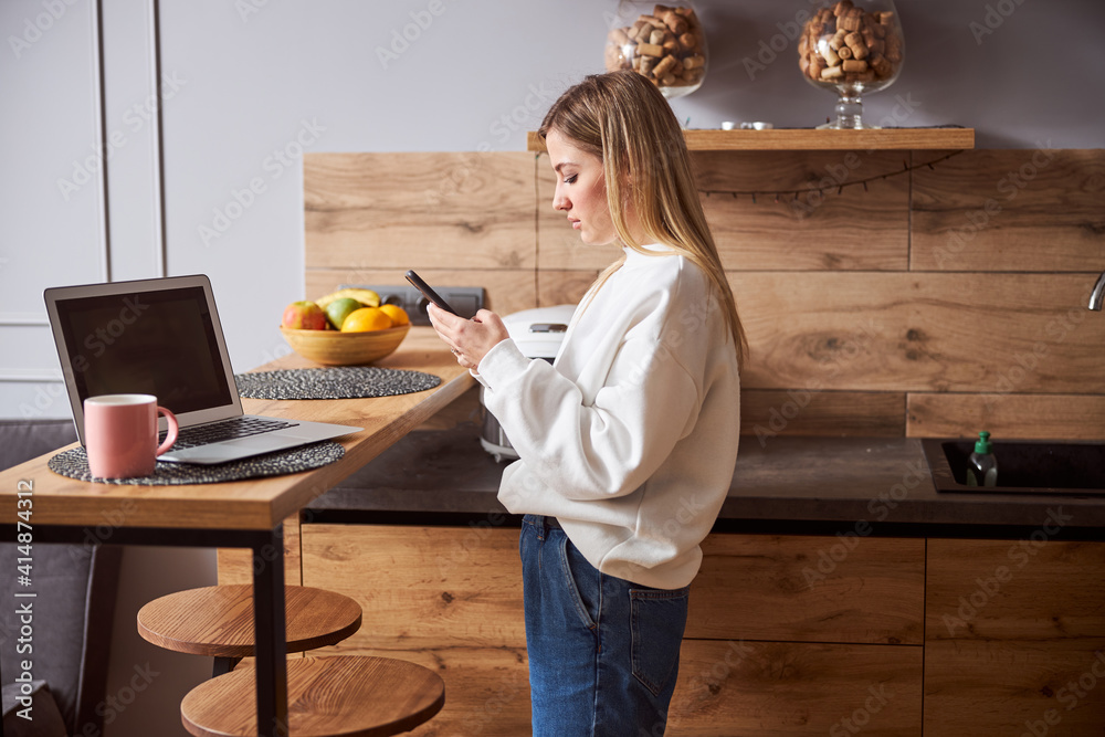 Female standing near the table and using smartphone Female standing near the table and using smartphone