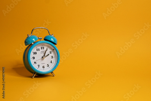 Blue alarm clock isolated on yellow