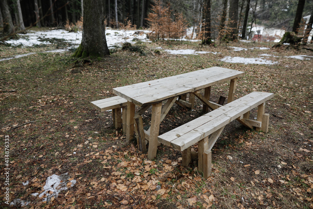 Wooden table and benches in the middle of a Romanian forest during a cold and rainy winter day.