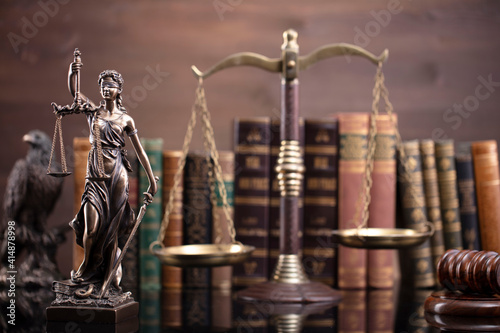 Law theme. Judge chamber. Judge’s gavel, scale, Themis sculpture and collection of legal books on the brown desk and the brown background.