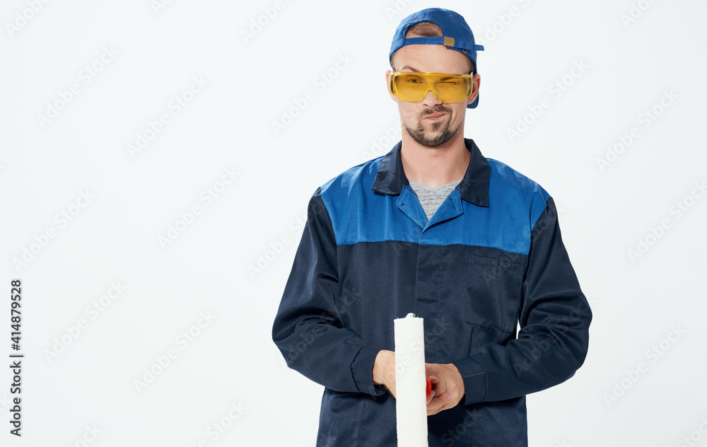 Man repairing paint roller blue suit and cap glasses Man repairing paint roller blue suit and cap glasses
