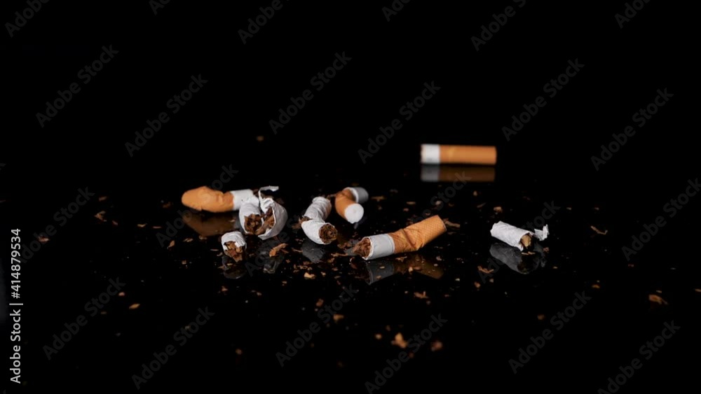 Used and stubbed out cigarettes falling on tobacco in slow motion.