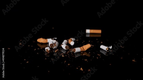 Used and stubbed out cigarettes falling on tobacco in slow motion.