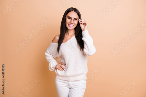 Photo of young woman happy positive smile confident hand touch eyeglasses isolated over beige color background