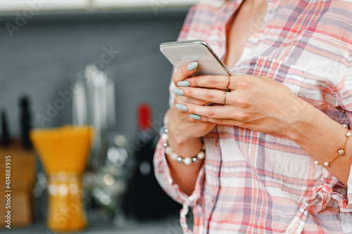 Unrecognizable woman using smartphone in kitchen close up