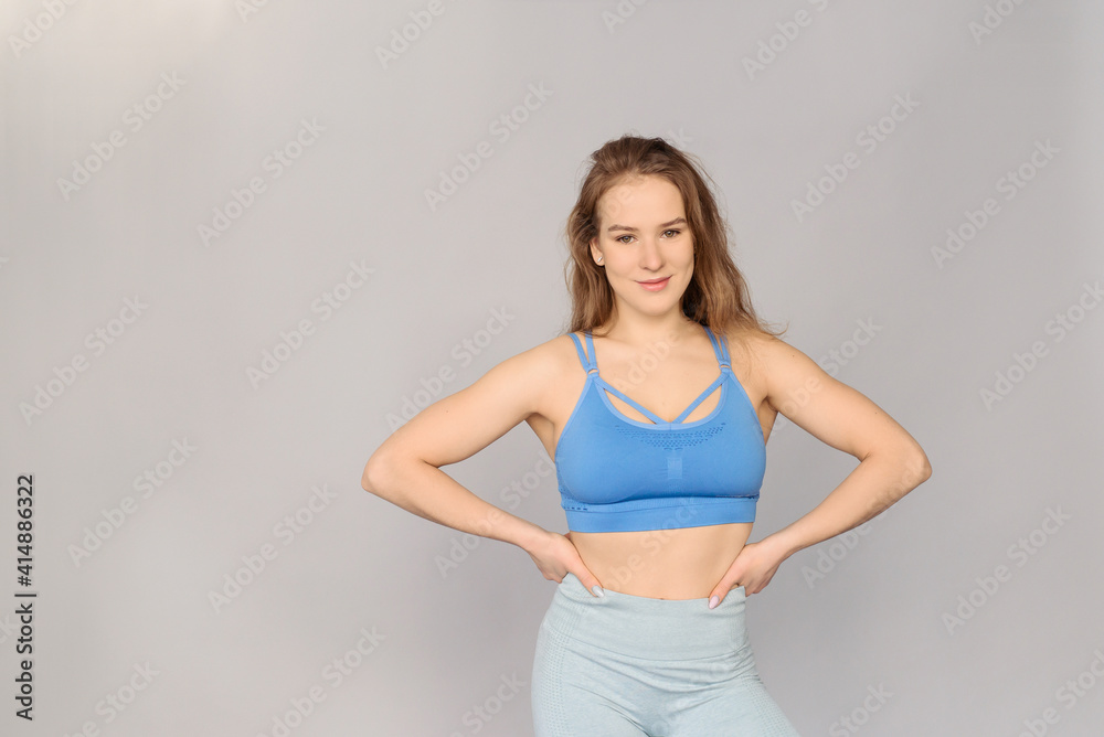 A young girl in a sports uniform on a gray background. Athlete and strong muscles. A young girl in a sports uniform on a gray background. Athlete and strong muscles.