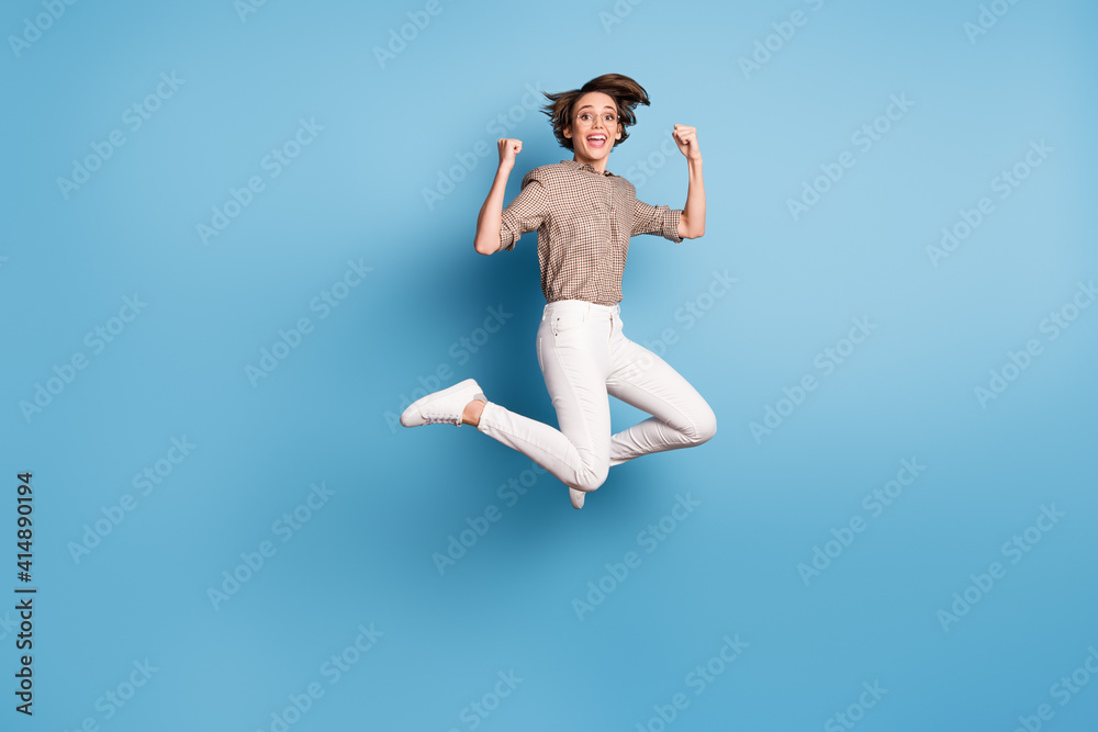 Full length portrait of carefree lady jumping fists up open mouth celebrate isolated on blue color background