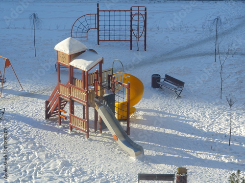 playground in the morning in winter in the snow lit by the sun is waiting for children and parents