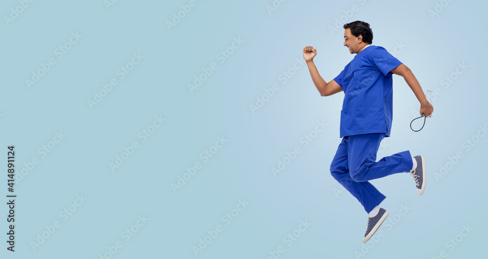 healthcare, profession and medicine concept - happy smiling indian doctor or male nurse in uniform with stethoscope jumping in air over blue background