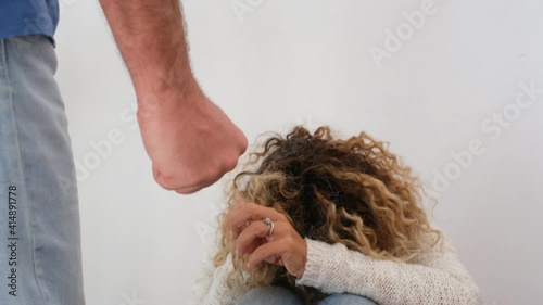 Woman violence abuse concept with female on the floor try to protect herself with stop word written on hands and man about to beatup her with closed punch - concept of victim at home photo