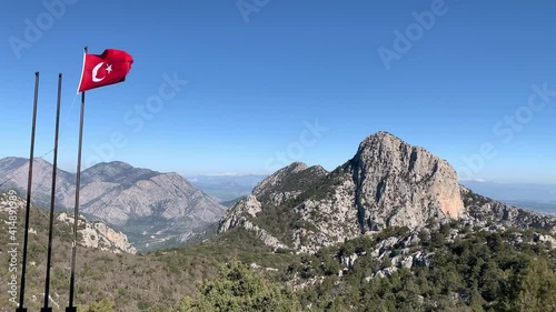 Flag of Turkey waving in the wind against deep blue sky and mountains. The national flag of Turkish flutters in the wind with nature landscape background. 4k 60 fps  photo