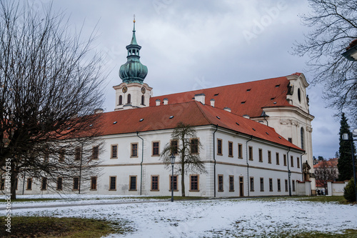 Baroque white benedictine monastery Brevnov with church, Medieval Basilica of St. Marquette, Garden and park, abbey under snow in winter day, Prague, Czech Republic