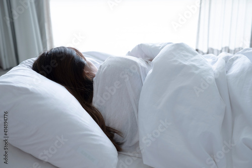 Back long black hair woman sleep or nap in afternoon. female wear white shirt sleeping on bed in bedroom and white blanket and white pillow in morning because good bedding sheet comfy and relax girl.