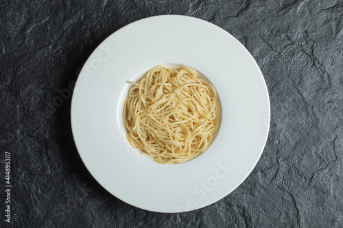 Delicious noodles in a white plate on a dark background