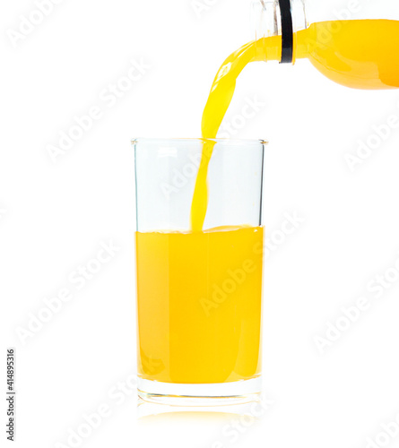 Yellow orange juice poured from a plastic bottle and put into a clear glass, the drink is processed from natural citrus fruit, contains vitamins and calcium, white background isolated.