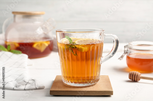 Hot tea with mint and lemon slices on white table, closeup