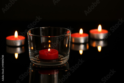 Wax candles burning on table in darkness. Space for text