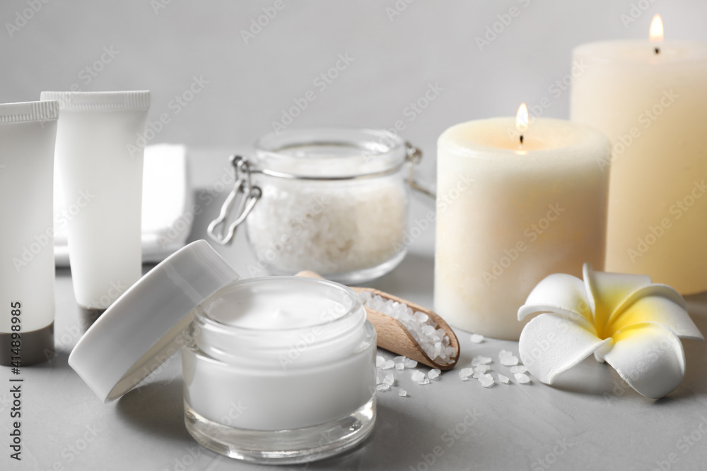 Composition with cosmetic products and candles on grey table Composition with cosmetic products and candles on grey table