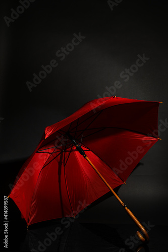 Open stylish red umbrella on black background