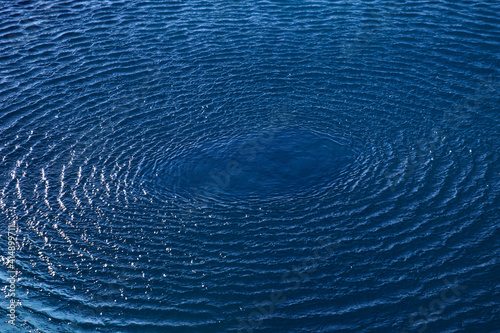 Splash: concentric circle waves on blue fresh sea water; color photo.