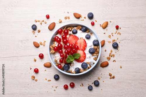 Delicious granola with fruits and nuts on wooden table, flat lay