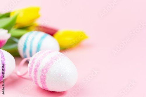 Easter painted eggs with tulips on a pink background. Copy space. Easter celebration concept.