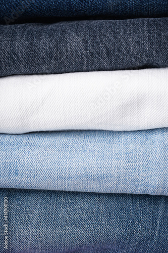 Stack of folded jeans, denim background, close-up