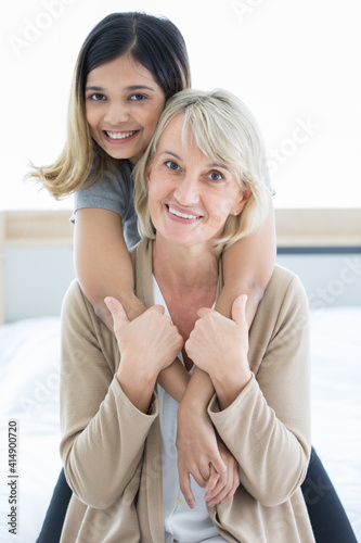 Happy mix skin family living together, adopted caucasian mother and Asian daughter cuddle each other with smiles. Idea for love and sharing time of stepmother, stepdaughter, mother or daughter in law photo