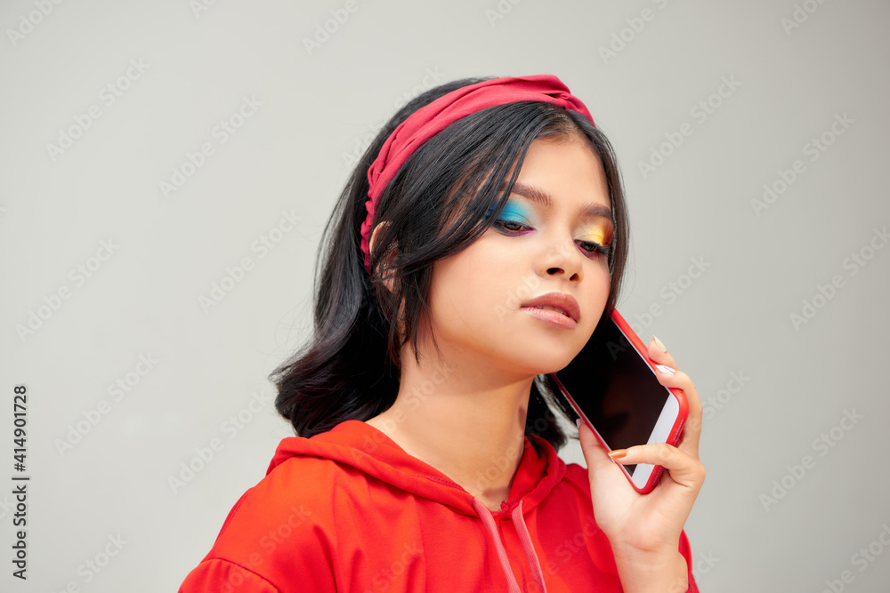 Naklejka premium Photo of young happy lady standing isolated over gray background talking by mobile phone