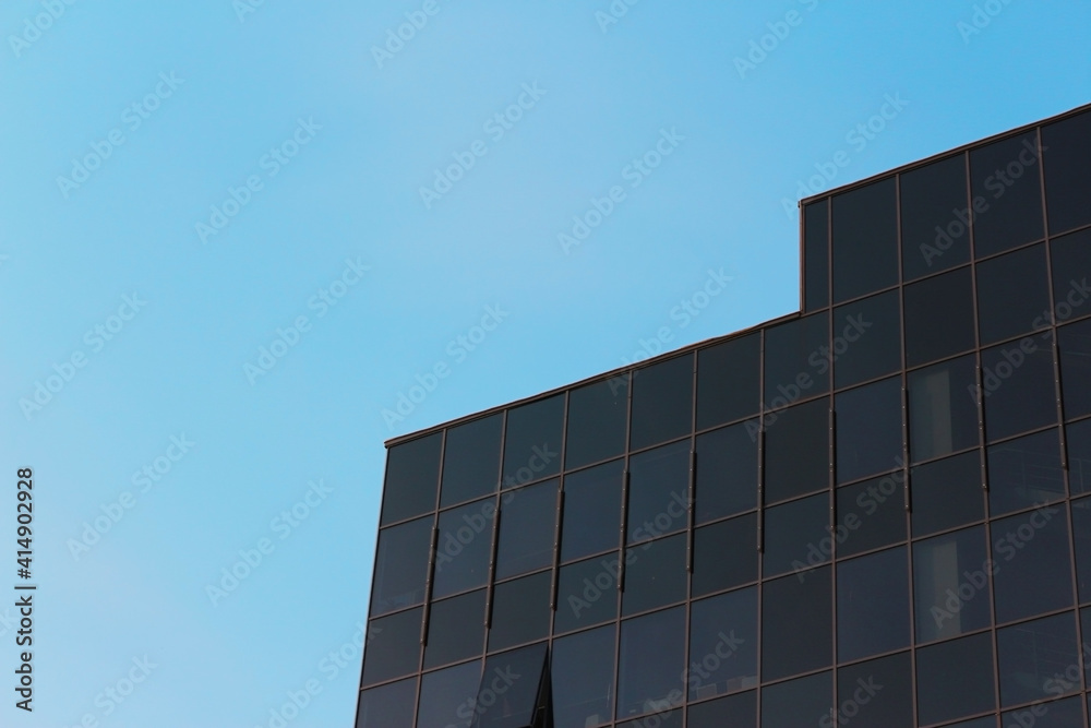 Part of a modern dark office building against the blue sky Part of a modern dark office building against the blue sky