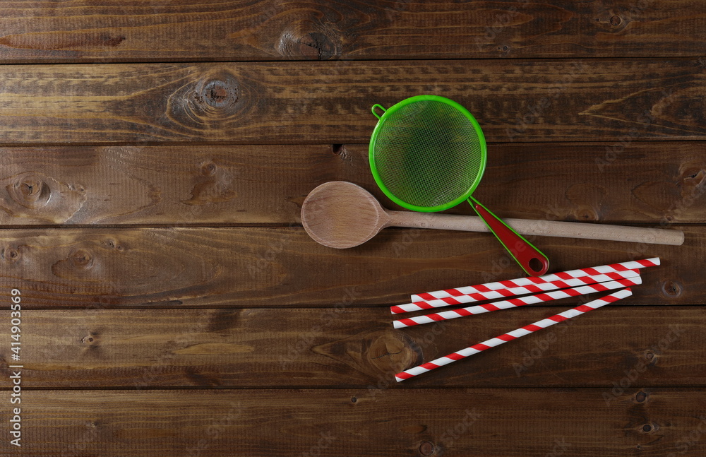 Wooden spoon, paper drinking straws and kitchen mesh strainer, sifter on wood planks table background and texture Wooden spoon, paper drinking straws and kitchen mesh strainer, sifter on wood planks table background and texture