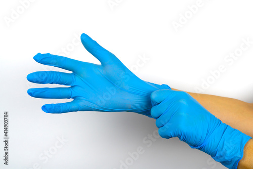Fototapeta Naklejka Na Ścianę i Meble -  Hands put on blue medical gloves on a white background.