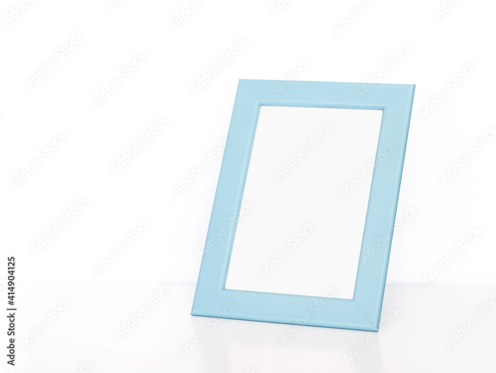 Blank light blue photo frame on white table. Interior decor mock up