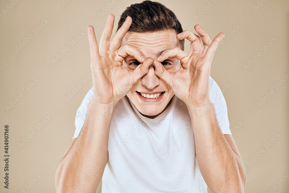 Emotional man white t-shirt gestures with hands lifestyle beige background