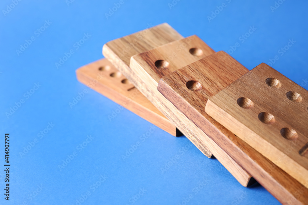 Fallen wooden domino tiles on blue background, closeup. Space for text Fallen wooden domino tiles on blue background, closeup. Space for text