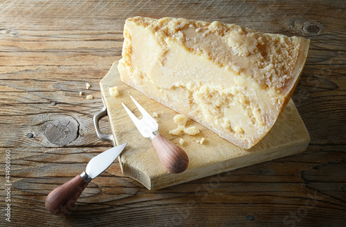 Pamigiano, Parmesan, Grana, aged cheese, knife and cutting board on rustic wooden background. photo