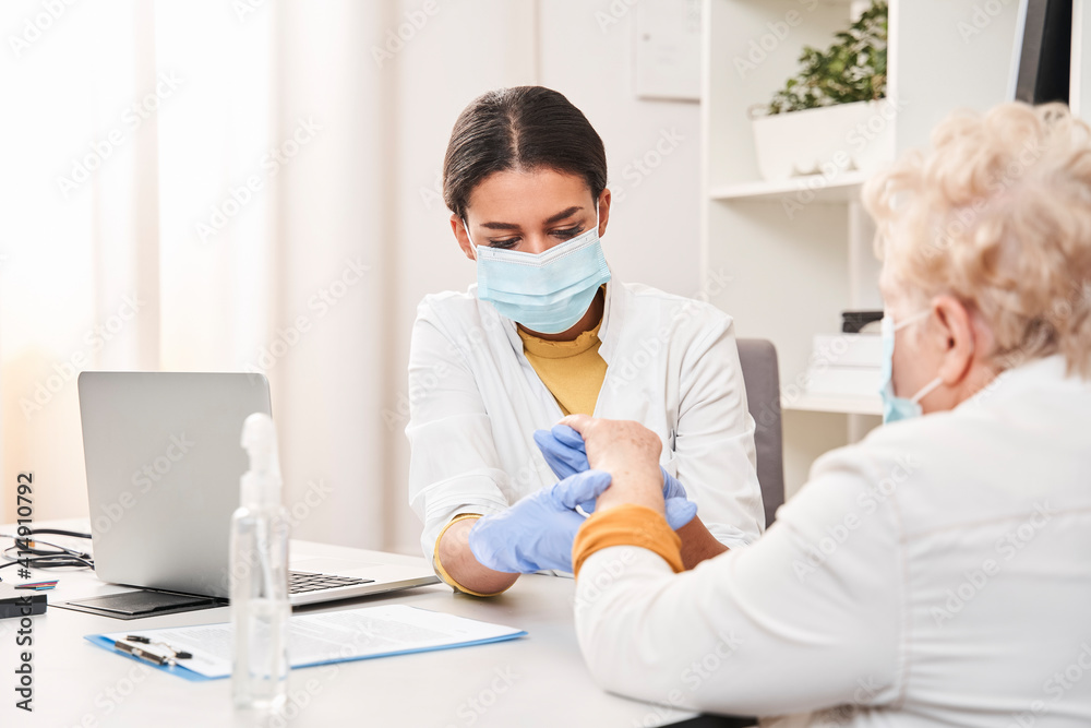 Fototapeta premium Doctor examining elderly patient while measuring her pulse