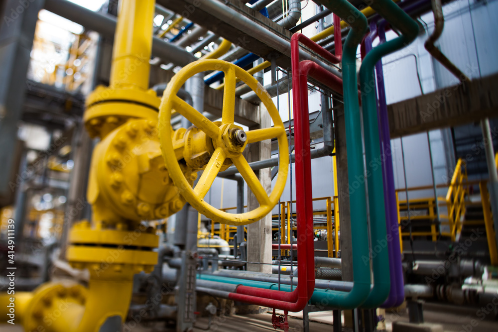 Oil refinery plant. Close-up of yellow gas valve and high-pressure tubes. Color pipes and grey pipelines on background. Small depth-of-field Oil refinery plant. Close-up of yellow gas valve and high-pressure tubes. Color pipes and grey pipelines on background. Small depth-of-field