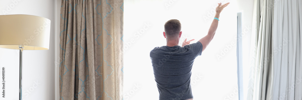 Man in gray suit stand near window in pose. Person do morning exercises in room. Man in gray suit stand near window in pose. Person do morning exercises in room.