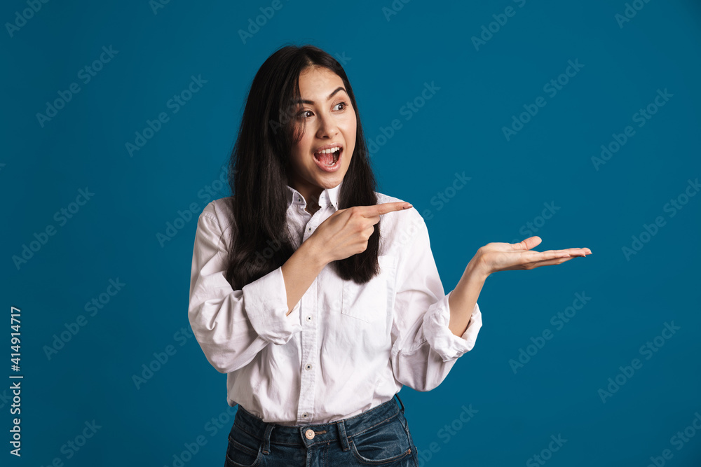 Excited beautiful asian girl holding and pointing finger at copyspace Excited beautiful asian girl holding and pointing finger at copyspace