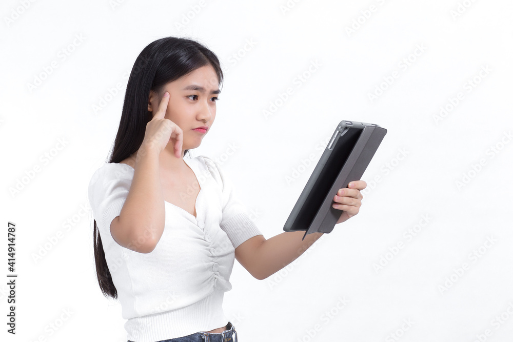Asian woman in a white shirt looks at a tablet in her hand during a conference call. She was pondering on something happily against the white background. Asian woman in a white shirt looks at a tablet in her hand during a conference call. She was pondering on something happily against the white background.