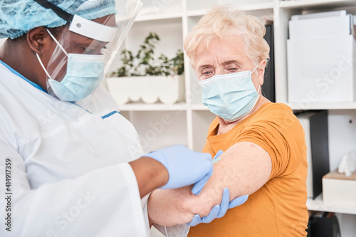 General practitioner vaccinating old patient