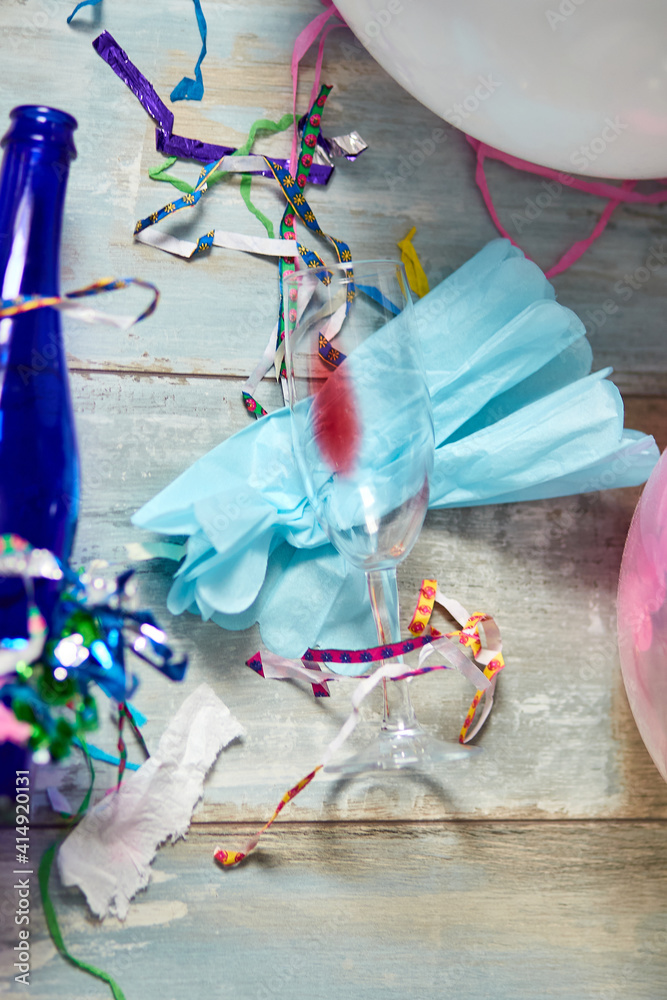 Fototapeta premium Top view of floor with after a party celebration with empty blue bottles, wine glass and party decorations, messy living room interior, After party chaos, birthday
