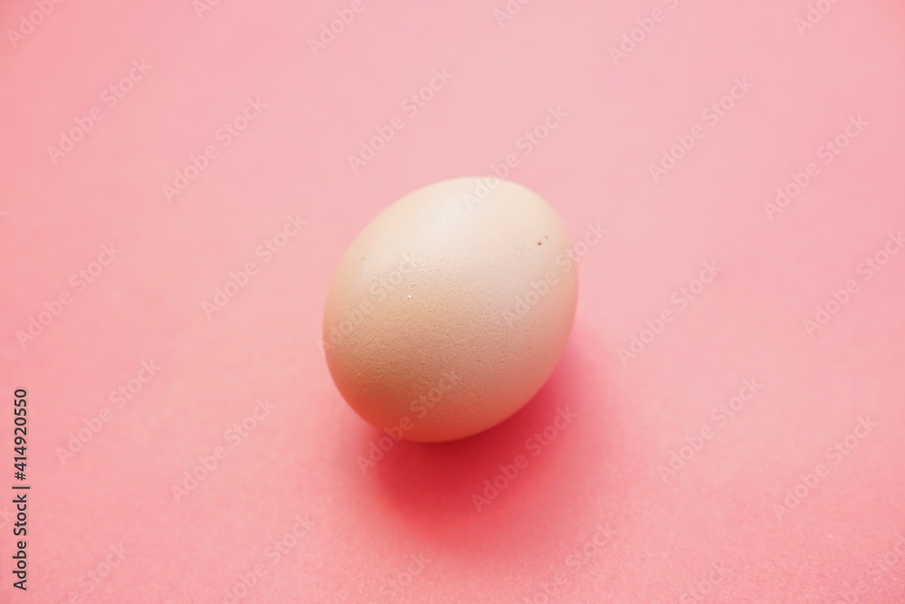 Eggs isolated on pink background give a warm effect. Eggs face the side. Egg wallpaper. Design, visual arts, minimalism. Egg template. Organic chicken egg concept. The concept of healthy organic food.