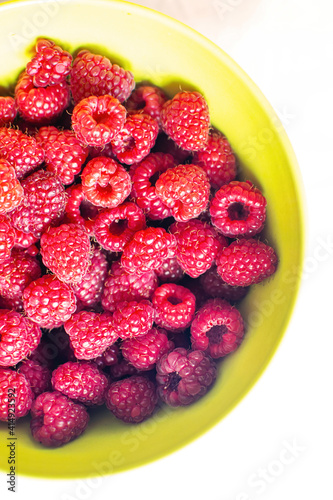 Close-up of ripe raspberry fruits on a bamboo plate on the table.